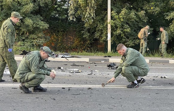 In this handout photo taken from video released by Investigative Committee of Russia on Sunday, Aug. 21, 2022, investigators work on the site of explosion of a car driven by Daria Dugina outside Mosco ...