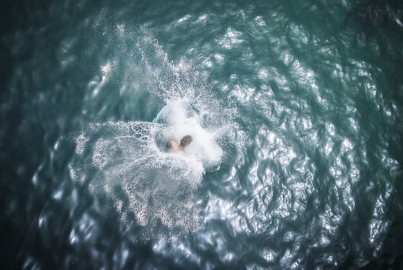 A man jumps into the river Limmat at Letten, as a heat wave reaches the country, in Zurich, Switzerland on Saturday, June 18, 2022. (KEYSTONE/Michael Buholzer)