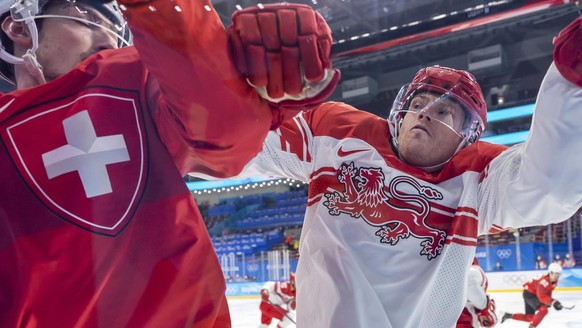 epa09750107 Denmark's Julian Jakobsen (R) checks Switzerland's Fabrice Herzog (L) during the Men's Ice Hockey preliminary round game between Switzerland and Denmark at the Beijing 2022 ...