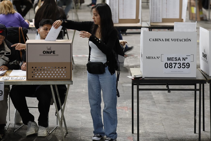 epa12884842 A Peruvian voter (C) residing in Barcelona casts her ballot for Peruvian general election at the polling station set up at Monjuic convention center, in Barcelona, northeastern Spain, 12 A ...