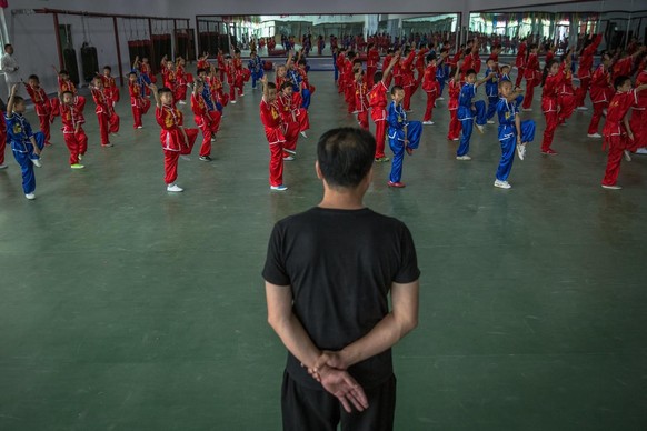 epa06154266 (03/29) Fu Jian Jie (C), the Chinese Traditional Martial Arts League Secretary General, looks as Chinese children practice the internal Chinese martial art Tai Chi during a training at the ...