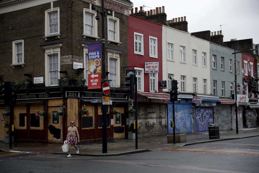 A man walks past temporarily closed shops and a pub in Camden Town, an area of London usually bustling with tourists and visitors to its market, Tuesday, Jan. 12, 2021, during England&#039;s third nat ...