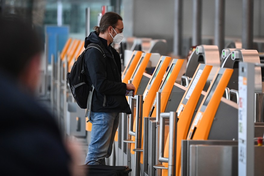 epa09607173 A traveller wearing an ffp-2 face mask checks in at the airport in Munich, Germany, 27 November 2021. The spread of a new potentially more dangerous variant of coronavirus, the B.1.1.529 C ...