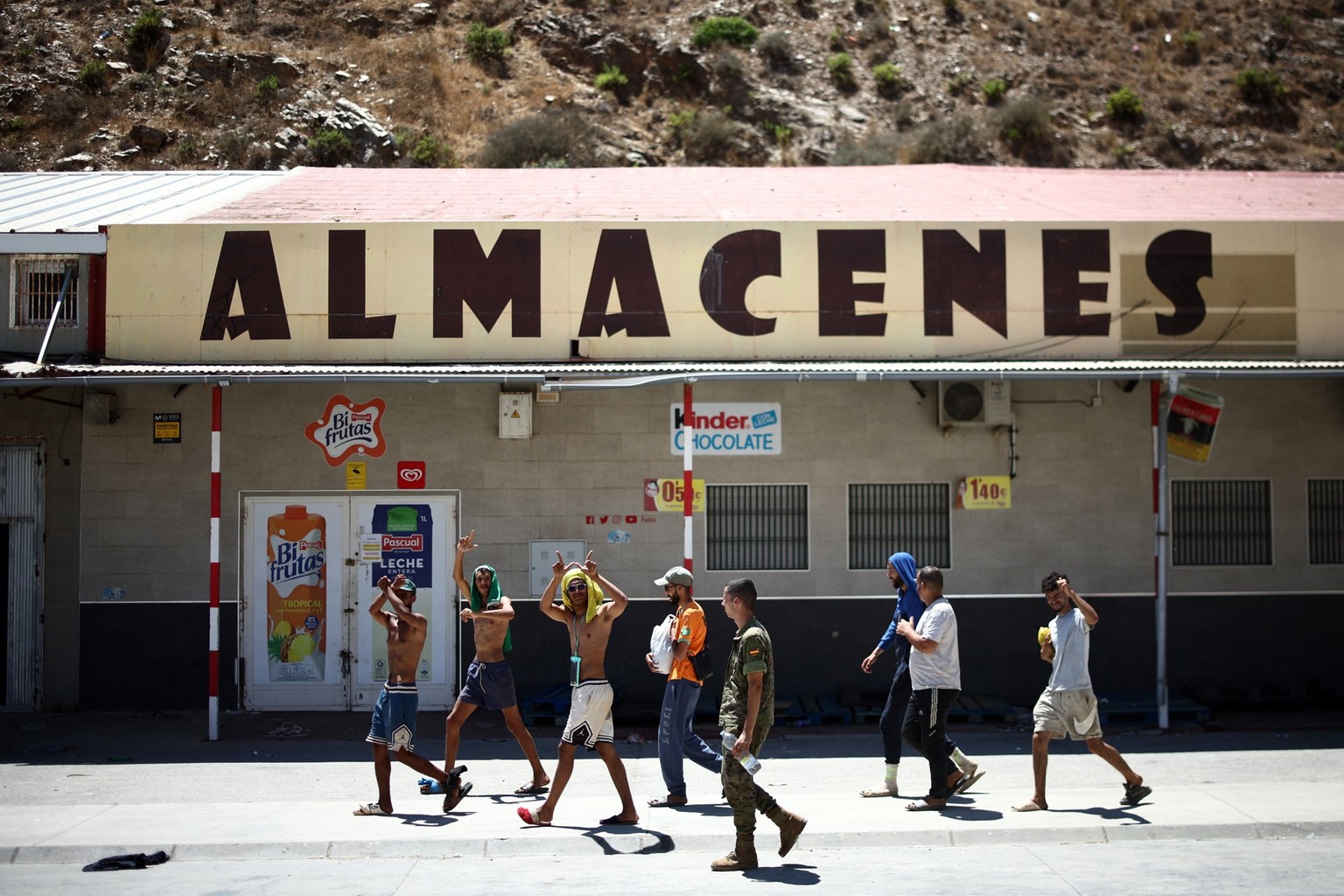 A group of migrants make their way back to Morocco from the short-stay centre CETI towards the border post, escorted by Spanish infantry soldiers, in the Spain's north African enclave of Ceuta, o ...