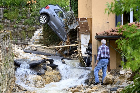 Une personne observe une carcasse de voiture bloquee a la verticale contre une maison apres un violent orage ce mercredi 23 juin 2021 a Cressier. Ce mardi soir 22 juin 2021 vers 19h00, de violentes in ...