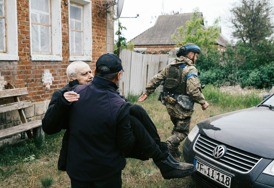 epa11336723 Local man Valentyn, 60, carries in his arms his disabled father, Viktor, 84, as they evacuate from territories bordering Russia, in the city of Vovchansk, Kharkiv region, northeastern Ukra ...