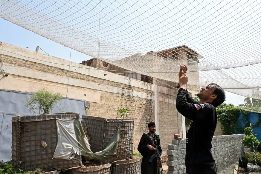 This photograph taken on August 4, 2026 shows security personnel fortifying a police post with Ukraine-style mesh barriers, as a new line of defence against militant drone and aerial attacks at Bara i ...