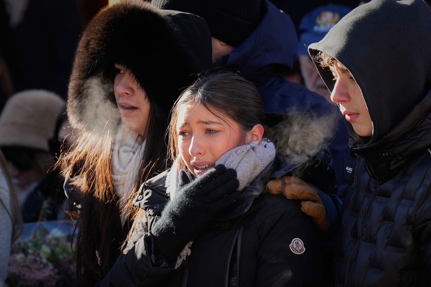 Youngsters cry as they attend a memorial march in Crans-Montana, Swiss Alps, Switzerland, Sunday, Jan. 4, 2026, after a devastating fire in Le Constellation bar left dead and injured during the New Ye ...