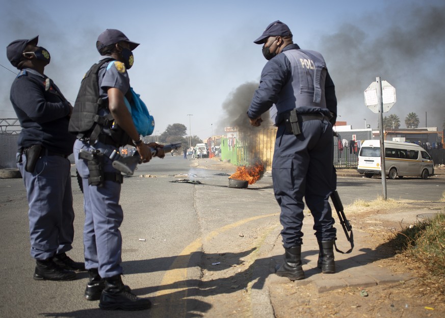 epa09336836 South African Police Force members stand near a road block during ongoing violent clashes in downtown Johannesburg, South Africa, 11 July 2021. President Zuma was arrested on Tuesday 06 Ju ...