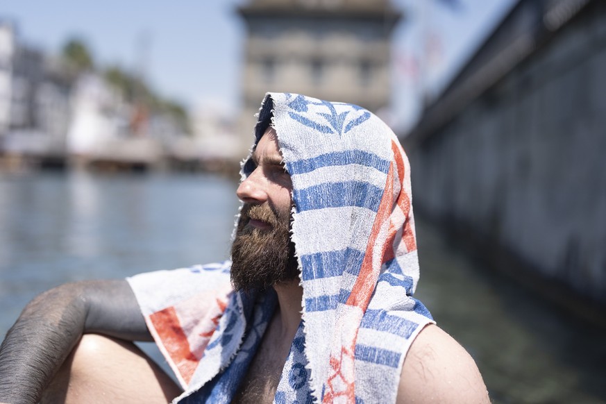 KEYPIX - Martin, Bauarbeiter von der Grossmuensterbaustelle, macht seine Mittagspause an der Limmat und schuetzt seinen Kopf gegen die Sonne mit seinem Badetuch, fotografiert am Freitag, 19. Juni 2026 ...