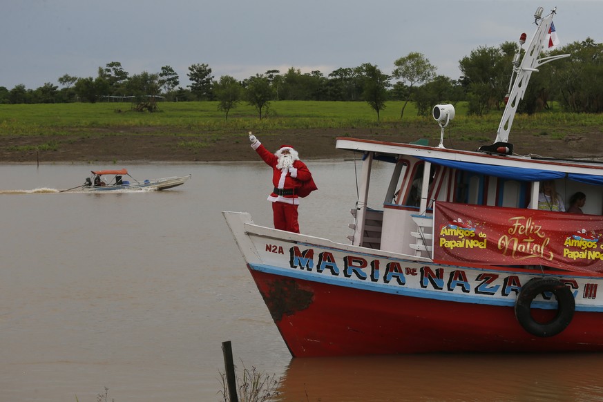 Un homme déguisé en Père Noël navigue sur le fleuve Amazone à bord d'un bateau pour visiter des communautés le long de la jungle et distribuer des cadeaux aux enfants du bassin amazonien, près de Careiro da Varzea, dans l'Etat d'Amazonas, au Brésil.