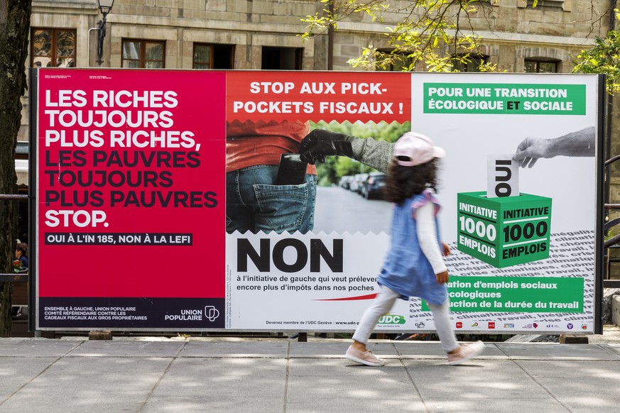 Une petit fille passe devant les affiches des partis politiques et des associations donnant leurs mots d&#039;ordre pour les votations federales, cantonales et communales du 18 juin, ce dimanche 4 jui ...