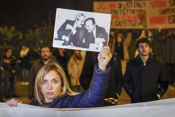 A woman displays a photograph that became iconic in Italy and shows top anti-mafia prosecutors Giovanni Falcone, left, and Paolo Borsellino, during a demonstration in the streets of Palermo, Sicily, I ...