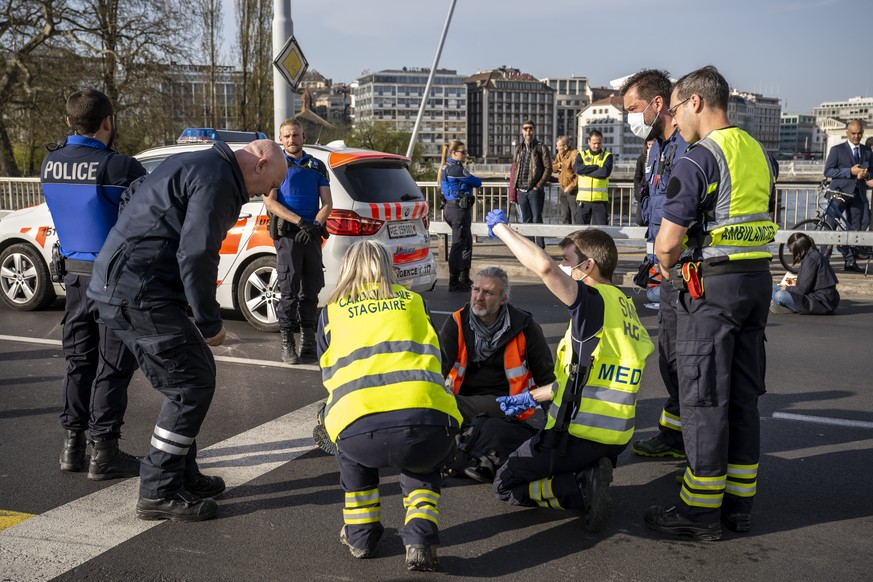 Paramedics and policemen are talking to a climate activist who glued his hand to the ground during the &quot;Renovate Switzerland&quot; roadblock action at the Mont-Blanc bridge, in Geneva, Switzerlan ...