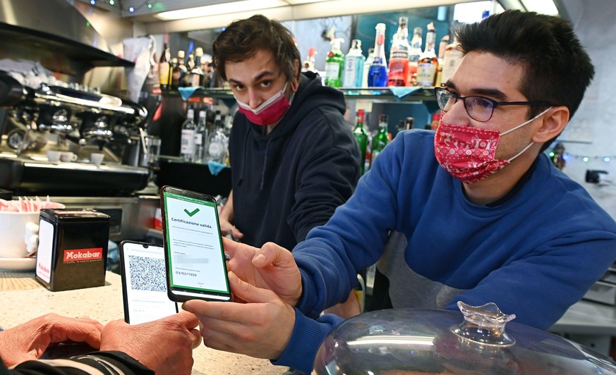 epaselect epa09657886 A bar owner checks the Green Pass of customer at the bar counter in Turin, Italy, 27 December 2021. The Italian government on 24 December imposed a series of new COVID-19 prevent ...
