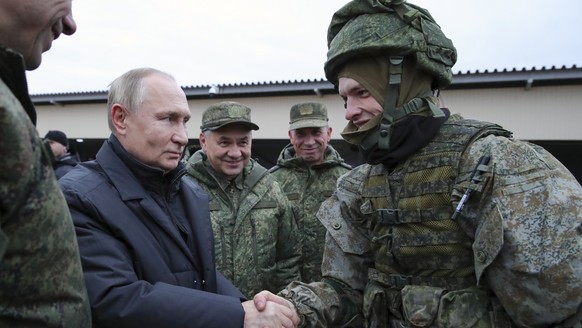 FILE - Russian President Vladimir Putin shakes hands with a soldier as he visits a military training centre of the Western Military District for mobilised reservists as Russian Defense Minister Sergei ...