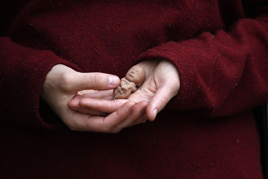 Melanie Wong holds a plastic fetus on Tuesday, April 12, 2022, outside the Hope Clinic for Women in Granite City, Ill. Wong, who opposes abortion, says she was standing outside the clinic to offer sup ...