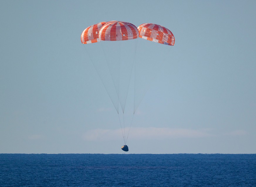 In this photo provided by NASA, the Orion spacecraft with Artemis II crewmembers aboard approaches the surface of the Pacific Ocean for splashdown off the coast of California, Friday, April 10, 2026.  ...