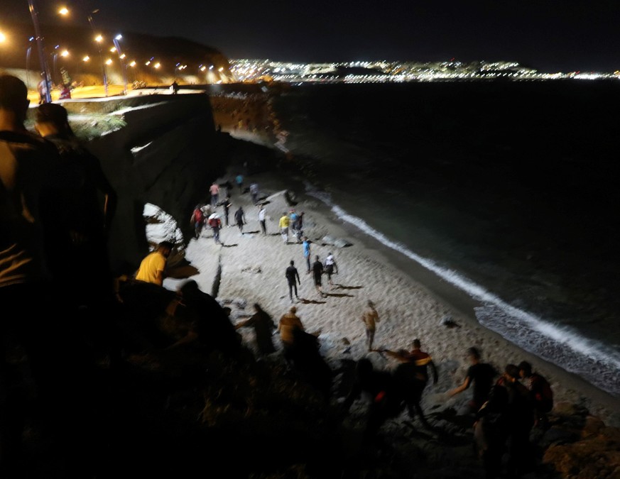 epa09207749 Hundreds of young Moroccans cross the border with Spain along the coast next to the town of Castillejos, also known as Fnideq, Morocco, 17 May 2021. The Spanish Government Delegation in Ce ...