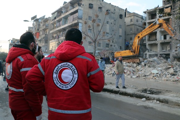 epa10453133 Two members of the Syrian Red Crescent watch rescue workers during rescue operations at Masharqa neighborhood of Aleppo, Syria, 07 November 2023. Thousands of people died and thousands mor ...