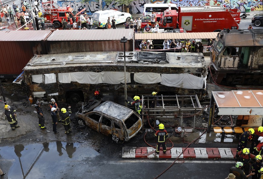epa12963264 Thai rescue workers extinguish a fire at a damaged car and a wrecked public bus following a collision between a freight train and a bus at the Airport Rail Link's Makkasan station in  ...