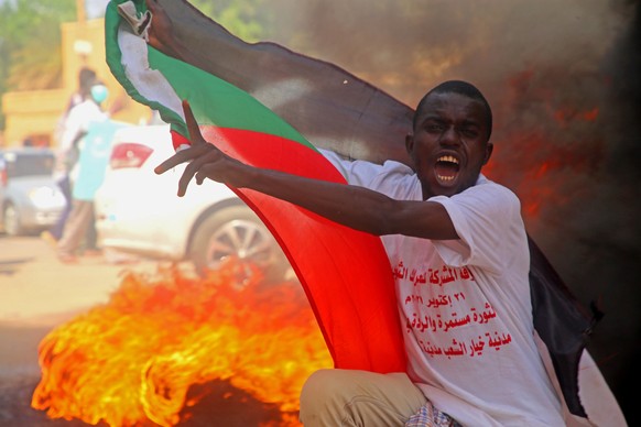 epaselect epa09537109 A protester holds a Sudanese flag and chants during demonstrations in support of the civilian government, in Khartoum, Sudan, 21 October 2021. Thousands of people marched during  ...