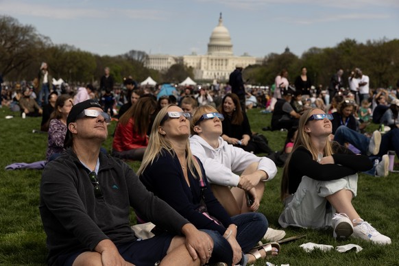 epaselect epa11266427 People on the National Mall look at a partial solar eclipse, with the US Capitol Building seen behind, in Washington, DC, USA, 08 April 2024. While reaching less than ninety perc ...
