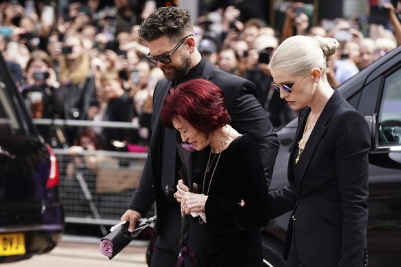 The family of Ozzy Osbourne from left, Jack Osbourne, Sharon Osbourne and Kelly Osbourne lay flowers and view the flowers left at the Black Sabbath Bridge bench on Broad Street in memory of Black Sabb ...