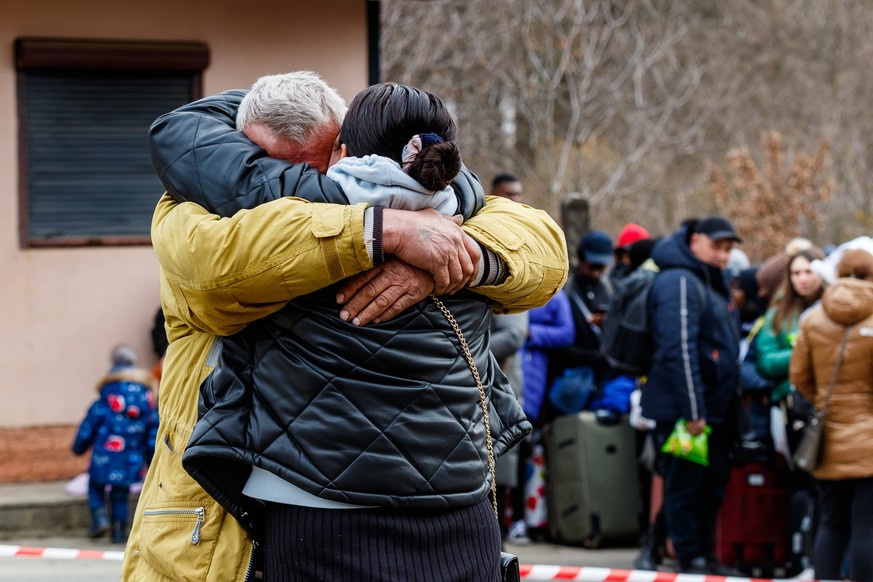 Un homme sur fond de réfugiés ukrainiens dit au revoir à sa femme qui fuit l&#039;agression russe.