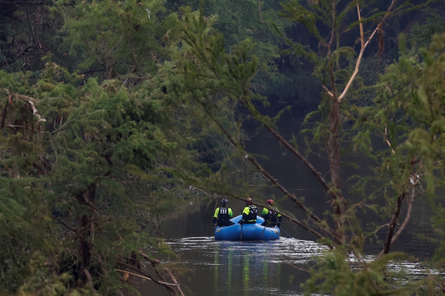 Rescuers paddle an inflatable boat as they search along a waterway following flash flooding, in Kerrville, Texas, U.S. July 6, 2025. REUTERS/Marco Bello