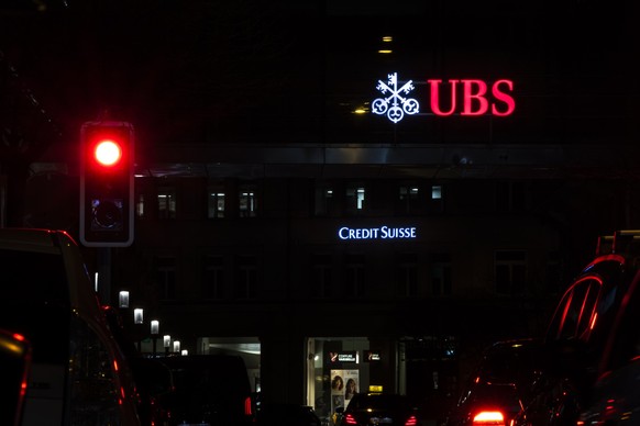 The illuminated logos of the Swiss banks Credit Suisse and UBS are seen on buildings next to traffic lights in Zurich, Switzerland on Saturday, March 18, 2023. (KEYSTONE/Michael Buholzer).