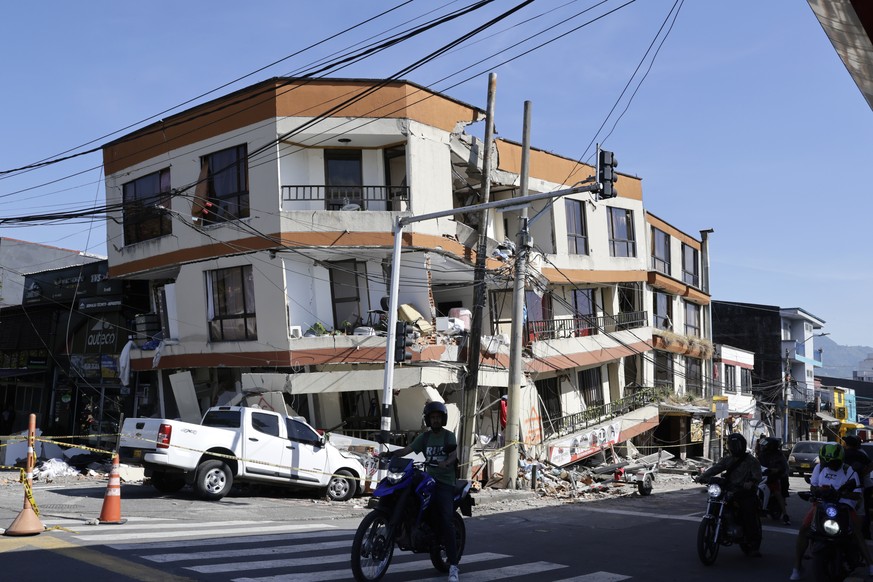 epa13161665 People ride motorcycles past a damaged building following a 7.4-magnitude earthquake, in Pereira, Colombia, 11 August 2026. At least 224 people have been killed and more than 1,300 others  ...
