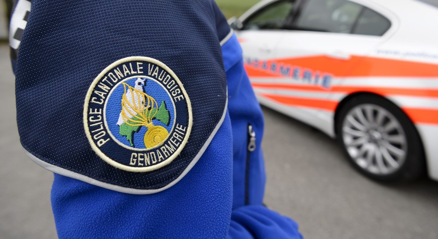 [Editor&#039;s note: photo mise-en-scene] Detail view of the uniform of a police officer of the cantonal police of Vaud, in the foreground, and a police car, in the background, photographed in Cugy, i ...