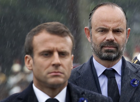 French President Emmanuel Macron and Prime Minister Edouard Philippe, right, stand at attention during a ceremony at the statue of General Charles de Gaulle to mark Victory Day in Paris, Wednesday, Ma ...