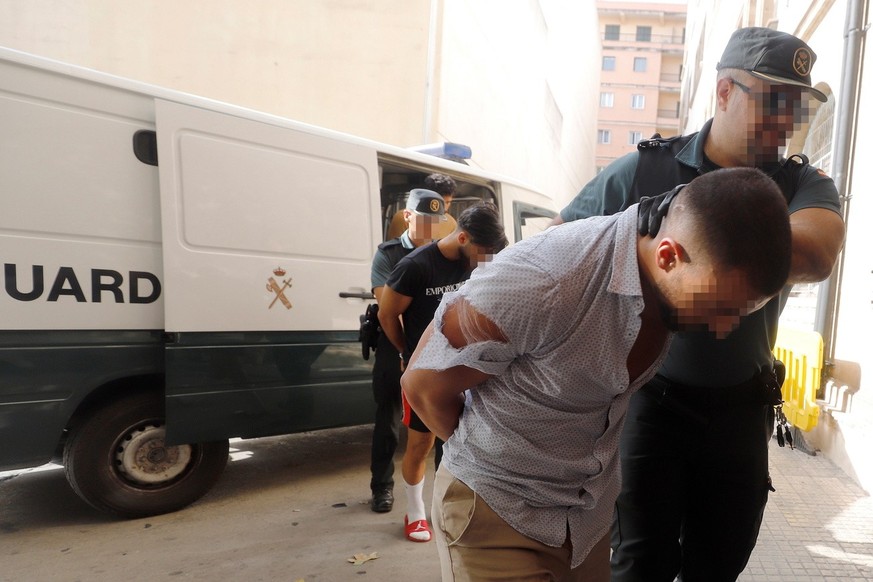 Four German tourists, who have been arrested over the alleged gang rape of a German woman at a hotel, are escorted by Spanish officials out of a Civil Guard van, in Cala Rajada, Mallorca, Balearic Isl ...