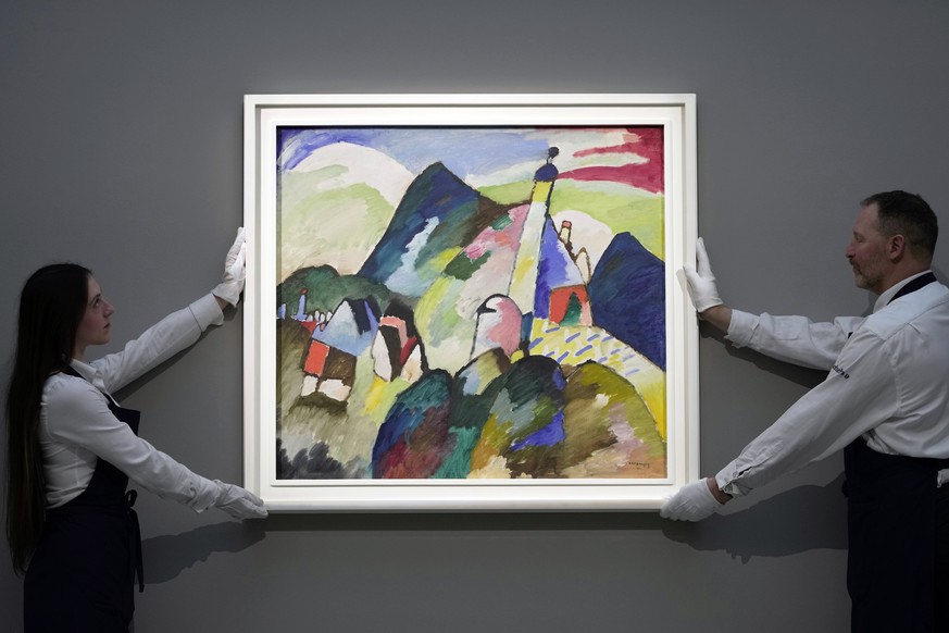 Members of staff hold the painting &quot; Murnau with Church II&quot; by Russian artist Wassily Kandinsky in 1910 is on display during a media preview of Sotheby&#039;s auction, in London, Wednesday,  ...