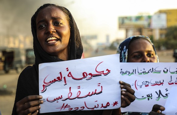 epa09547399 Sudanese protesters hold placards reading, 'Military government down', as they chant slogans next to burning tires during a demonstration in the capital Khartoum, Sudan, 26 October 2021. P ...
