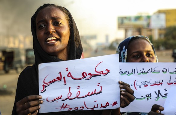 epa09547399 Sudanese protesters hold placards reading, &#039;Military government down&#039;, as they chant slogans next to burning tires during a demonstration in the capital Khartoum, Sudan, 26 Octob ...