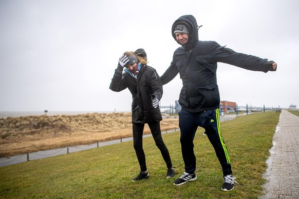 11.03.2021, Niedersachsen, Norddeich: Sandy und Daniel stehen bei starken Wind auf dem Deich. Foto: Sina Schuldt/dpa +++ dpa-Bildfunk +++ (KEYSTONE/DPA/Sina Schuldt)