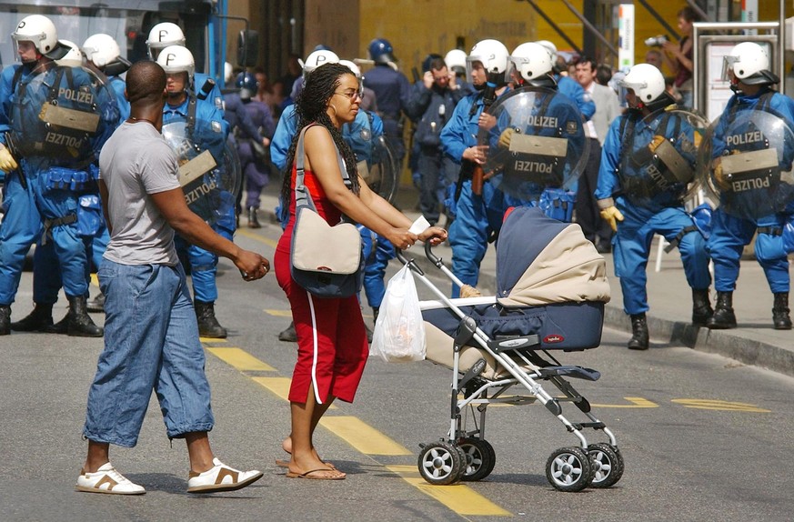 A couple passes by a line of Swiss riot police in the center of Geneva, Sunday, June 1, 2003. Several thousands of anti-globalisation demonstrators arrived to Geneva to protest against the G8 summit w ...