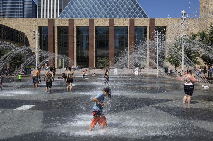 Les gens se rafraîchissent dans la piscine de l'hôtel de ville, alors que les températures ont atteint 37 degrés Celsius à Edmonton, en Alberta, le mercredi 30 juin 2021. (Jason Franson/The Canadian Press via AP)