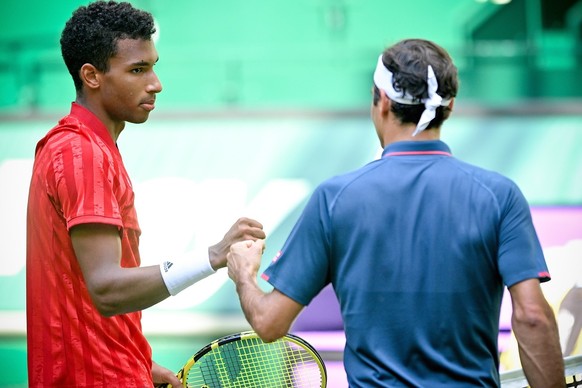 epa09276702 Felix Auger-Aliassime of Canada (L) and Roger Federer of Switzerland (R) fist bump after their round of 16 match against at the ATP Tennis Tournament Noventi Open in Halle (Westphalia), Ge ...