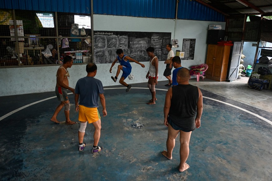 This photo taken on May 13, 2025 shows players taking part in a game of the traditional Myanmar sport of chinlone at a court in Yangon. Mastering control of the rising and falling rattan chinlone ball ...