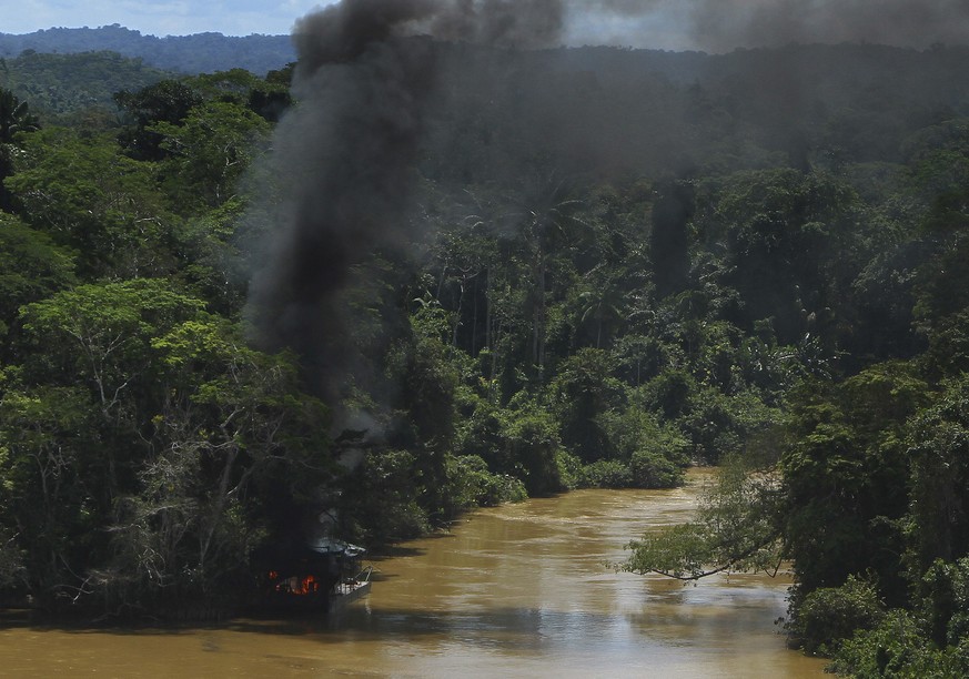 Une fumée noire s'élève d'un site d'orpaillage détruit.