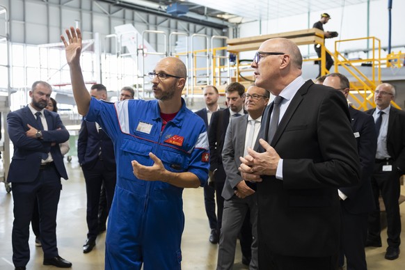 Bundesrat Martin Pfister, rechts, diskutiert mit Marco Bettini, Wartungs-Verantwortlicher, links, bei einem Besuch in der Halle fuer die Wartung der F/A-18 Flugzeuge, waehrend einem Rundgang auf dem M ...