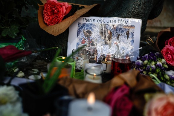 epa12514516 Candles burn among floral tributes for the victims of the November 2015 attacks, at a memorial site in the Place de la Republique, Paris, France, 09 November 2025. Ten years ago 130 people ...