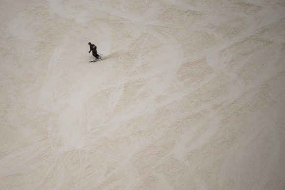 A skier descends at the Pizol ski resort on a slope partially covered with Sahara dust, in Wangs, Switzerland, Tuesday, March 15, 2022. (KEYSTONE/Gian Ehrenzeller)