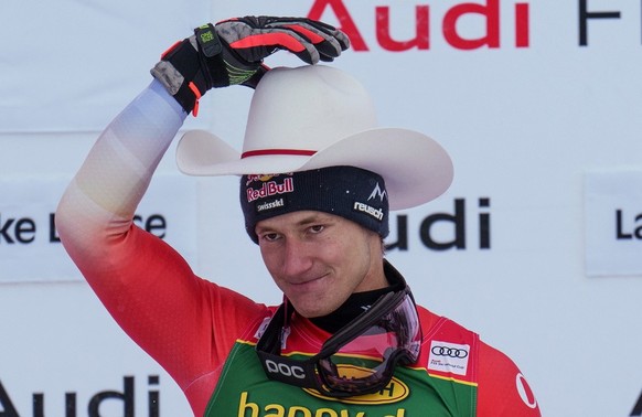 epa10333480 Marco Odermatt of Switzerland takes first place and tries on a cowboy hat as part of his prize for winning the Men&#039;s Super-G race at the FIS Alpine Skiing World Cup in Lake Louise, Al ...