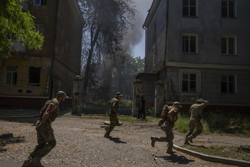 FILE - Ukrainian soldiers run after a missile strike hit a residential area, in Kramatorsk, Donetsk region, eastern Ukraine, Thursday, July 7, 2022. Injured residents sat dazed and covered in blood. A ...