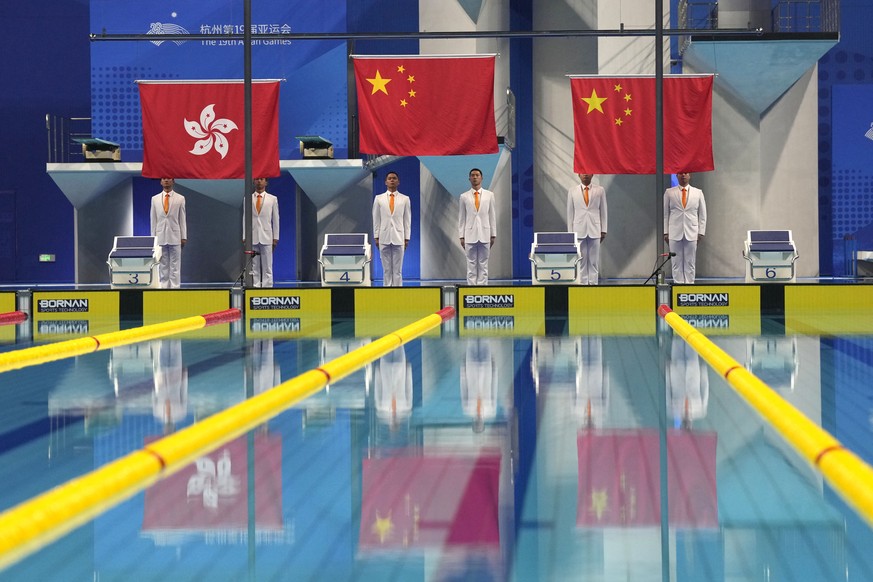 Chinese and Hong Kong flag are being hoisted during the victory ceremony for the women&#039;s 50m freestyle swimming at the 19th Asian Games in Hangzhou, China, Thursday, Sept. 28, 2023. (AP Photo/Lee ...
